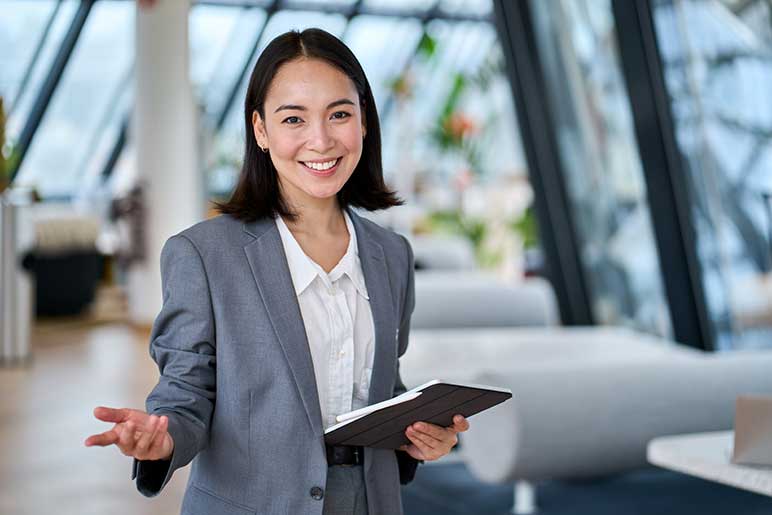 Photo of happy, young saleswoman looking at camera welcoming client.